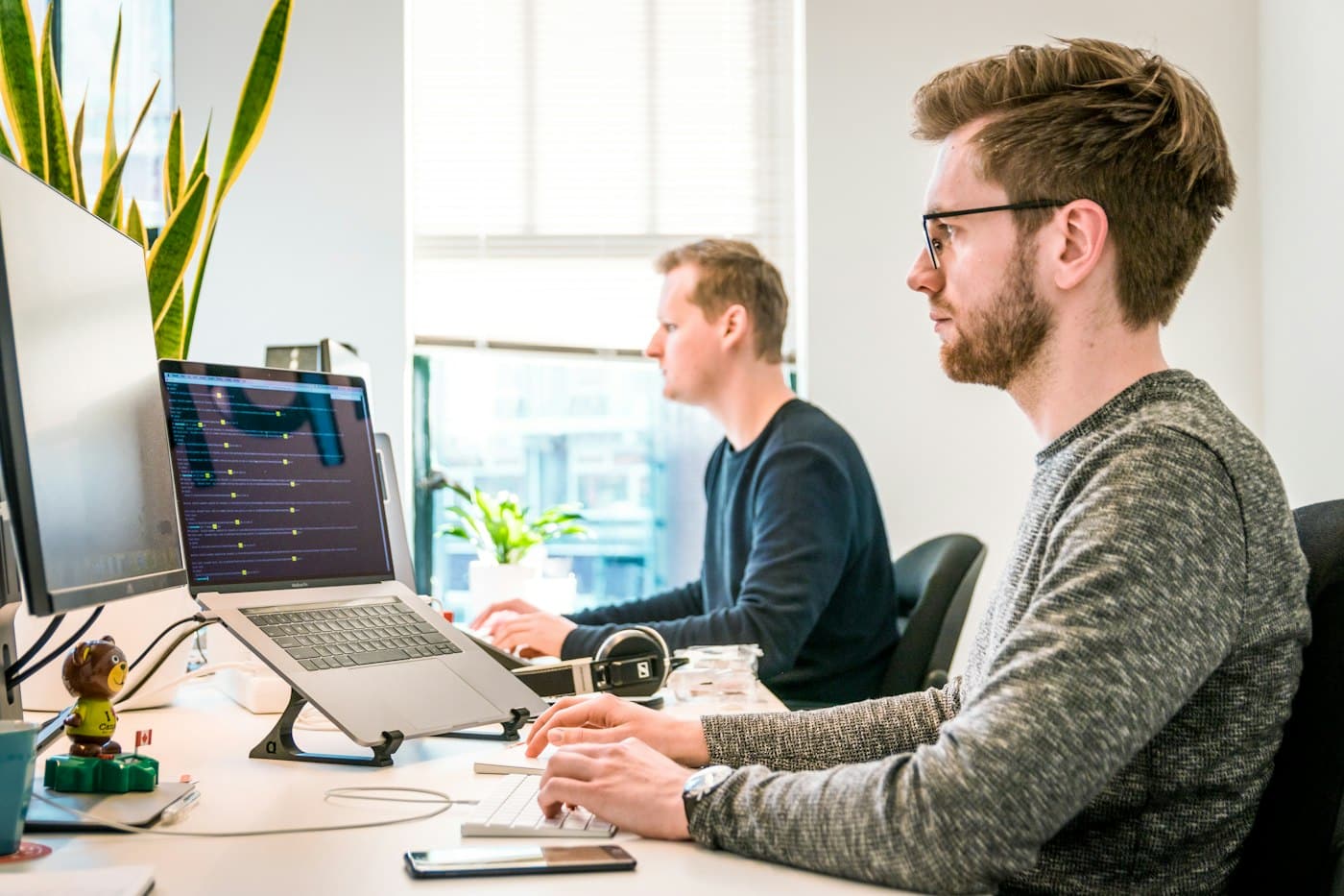 Two engineers reviewing code together on large monitors