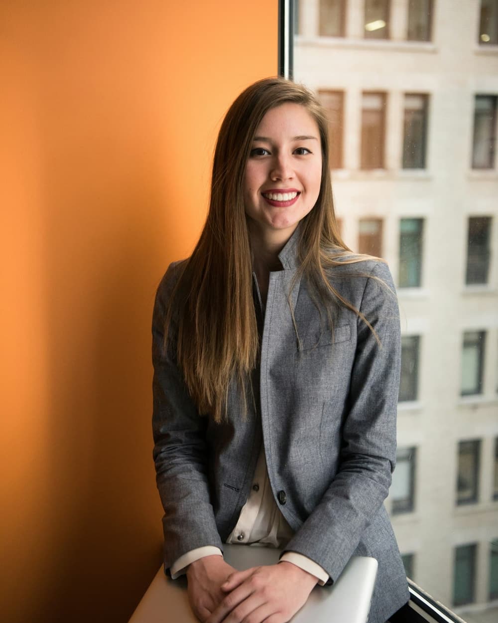A founder in a grey blazer smiling in an office