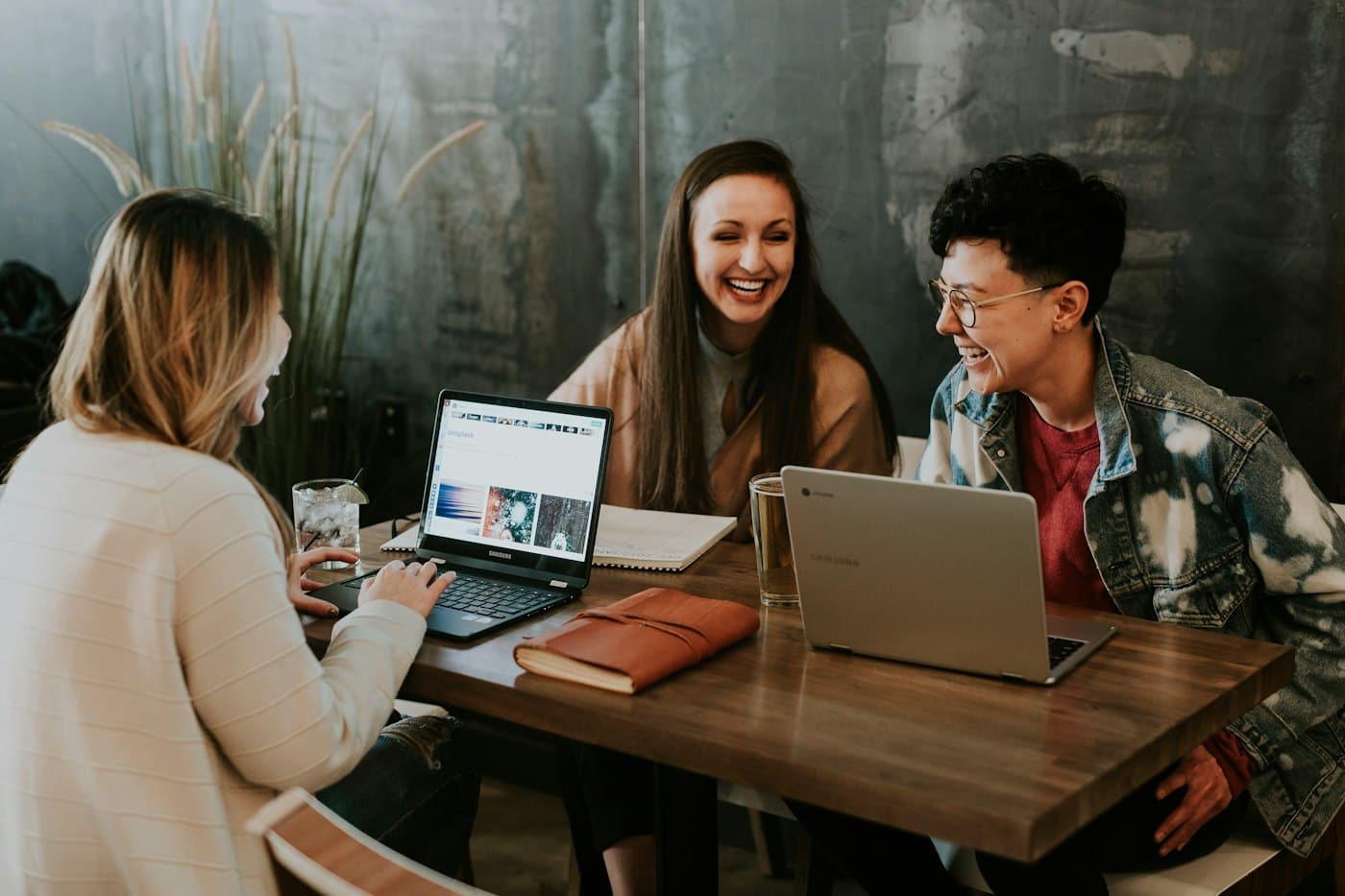 Two founders smiling at a laptop in a cafe