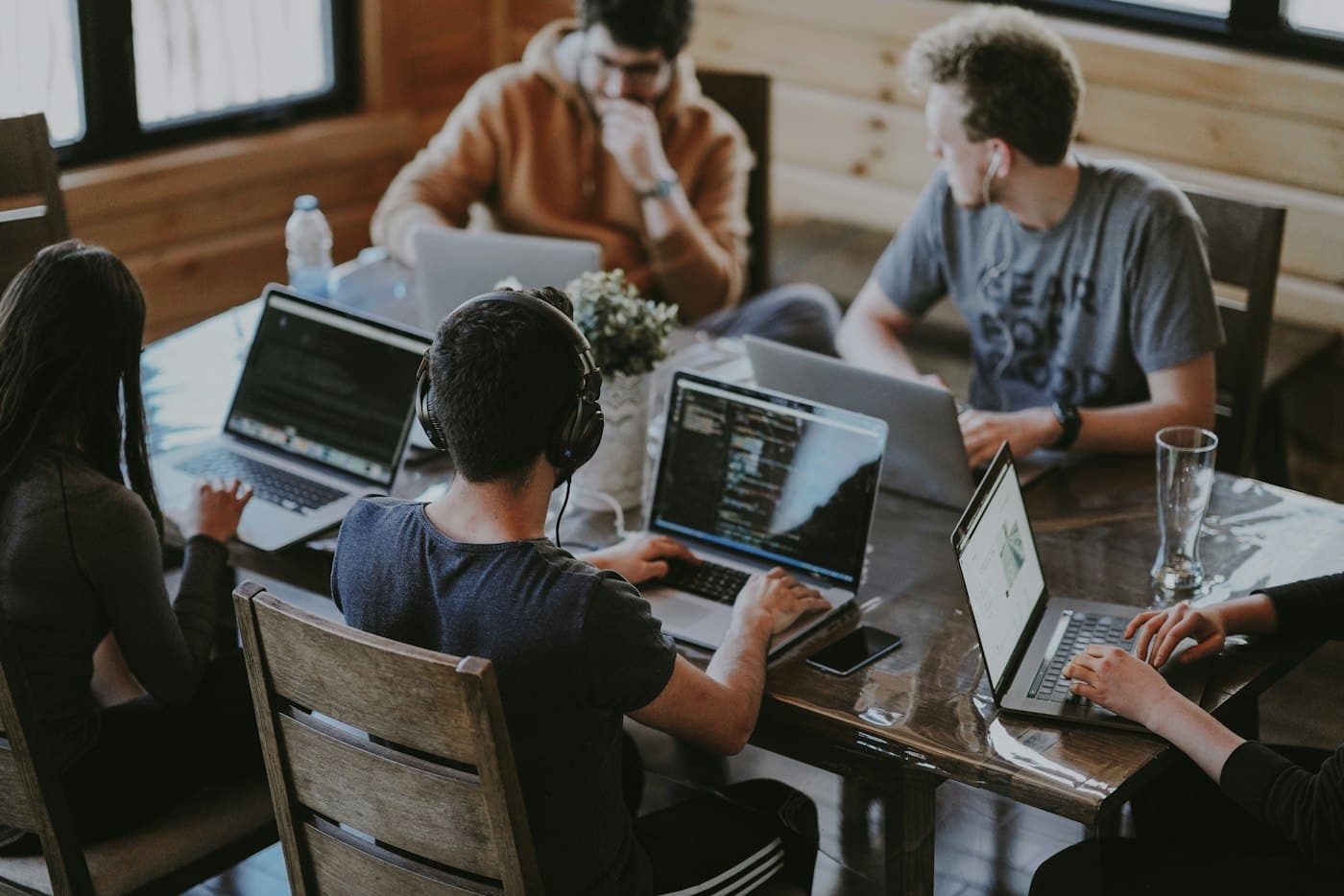 A startup team working on laptops around a wooden table