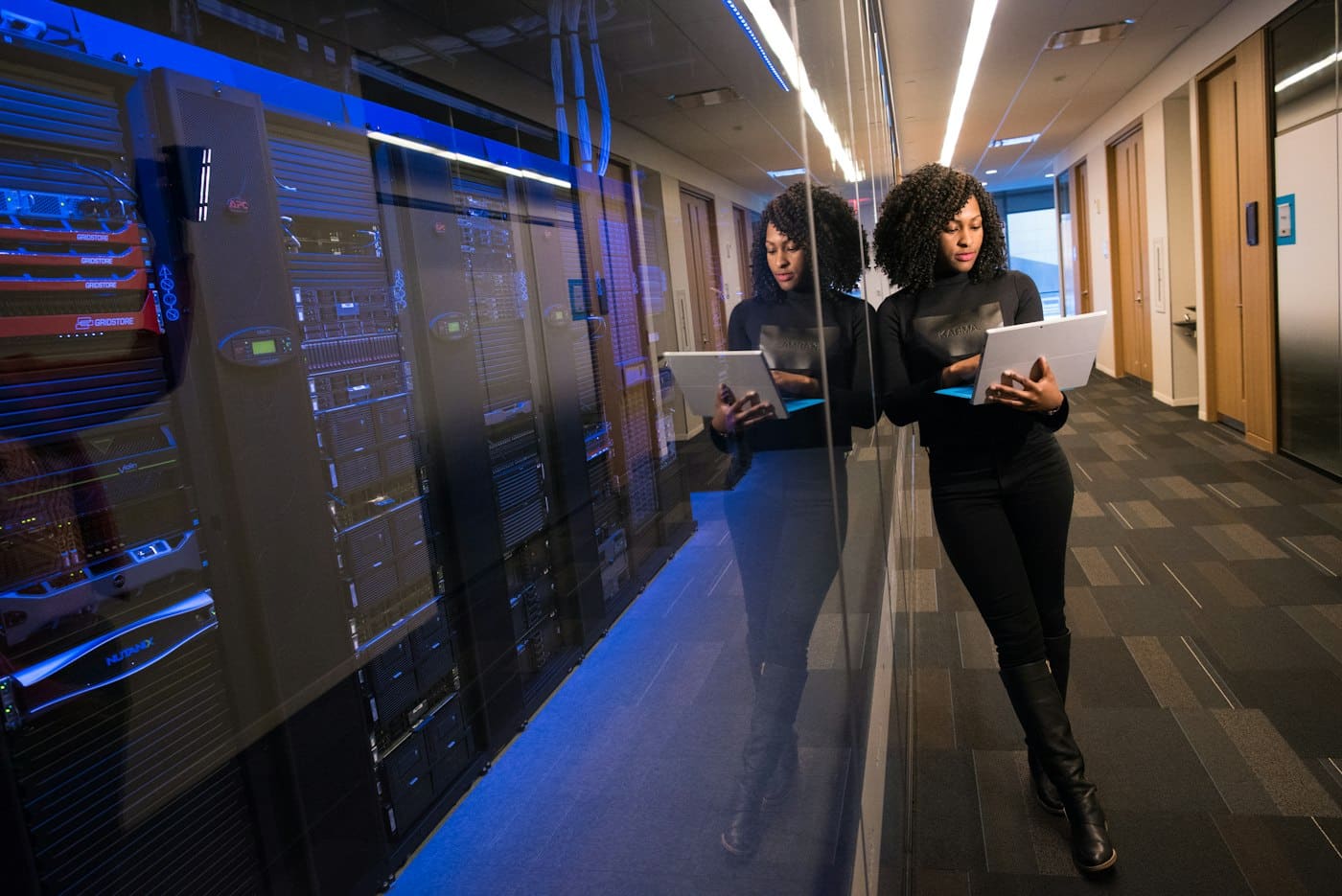 An engineer holding a laptop in a corridor of server racks